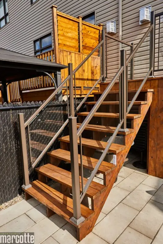 Terrasse en pierre adjacente à un deck en bois assortie d’une pergola
