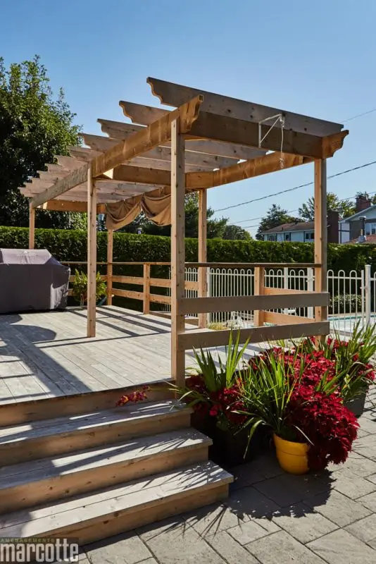 Terrasse en pierre adjacente à un deck en bois assortie d’une pergola