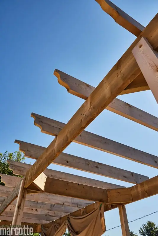 Terrasse en pierre adjacente à un deck en bois assortie d’une pergola
