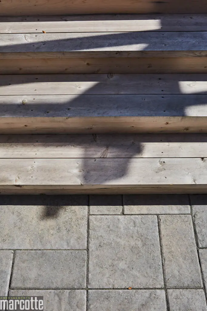 Terrasse en pierre adjacente à un deck en bois assortie d’une pergola