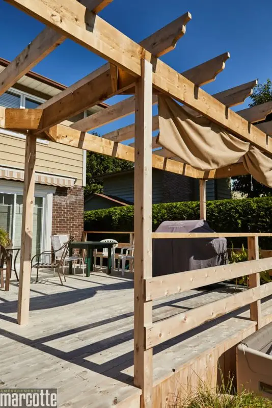 Terrasse en pierre adjacente à un deck en bois assortie d’une pergola