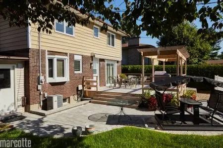 Terrasse en pierre adjacente à un deck en bois assortie d’une pergola
